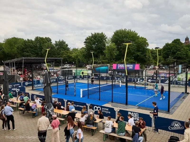 Bezoekers kijken bij een outdoor padelbaan tijdens het Padel Copa-evenement